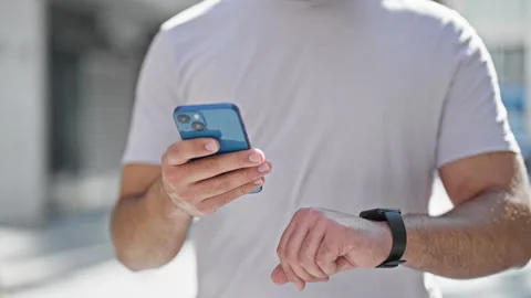 Young latin man using smartphone and smartwatch at street Stock Footage 247376817