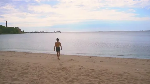 Young latin man walking on a beach with calm water and then running back. 4.. Stock Footage 234560171