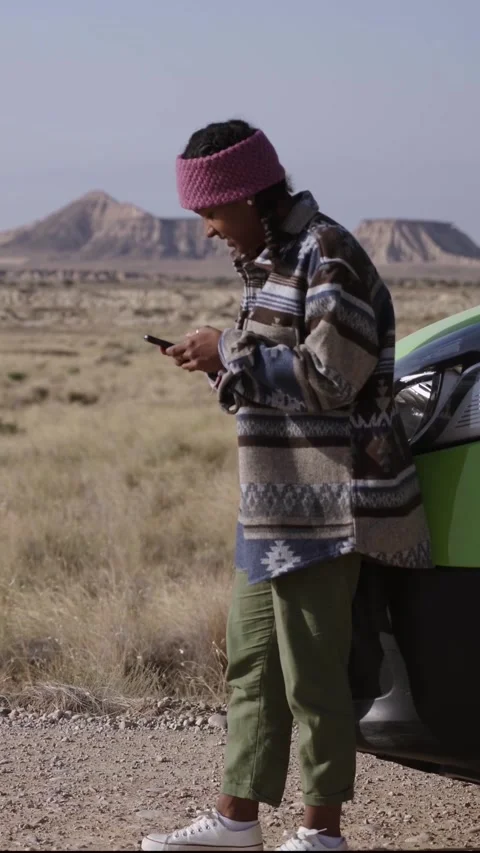 Young latina girl using cell phone leaning bumper camper travels alone on road Stock Footage 255622860