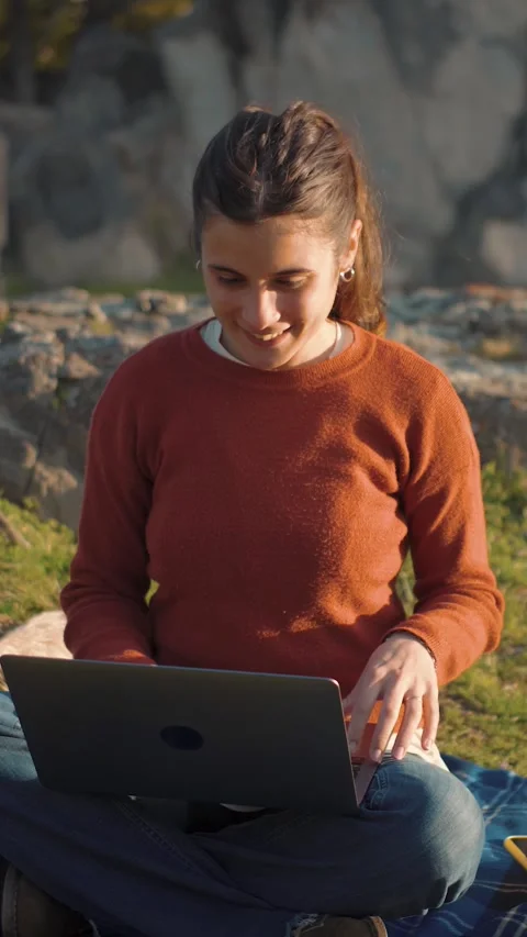 Young Latina student using her laptop while sitting in a park, representing educ 스톡 동영상 347082402