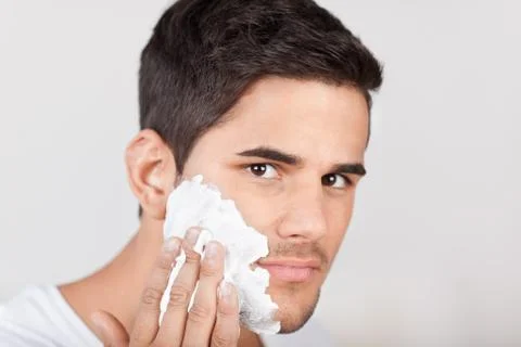 Young latino man applying shaving cream Stock Photos