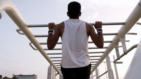 Young latino man doing pull ups in an outdoors calisthenics park Stock Footage 256420240