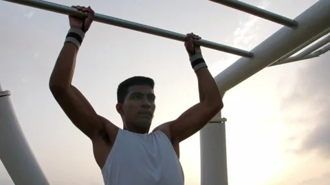 Young latino man doing pull ups in an outdoors calisthenics park Stock Footage 256422013