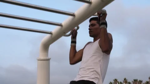 Young latino man doing pull ups in an outdoors calisthenics park Stock Footage 256422545