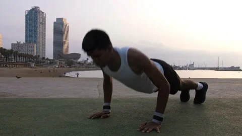 Young latino man doing push ups by the beach during sunrise Stock Footage 256423365
