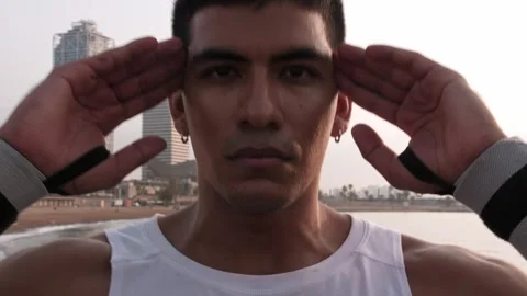 Young latino man doing sit ups by the beach looking at the camera Stock Footage 256426685