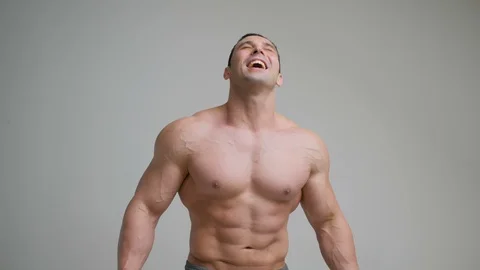 Young laughing muscular bodybuilder posing and looking at camera, isolated on Stock Footage 123251153