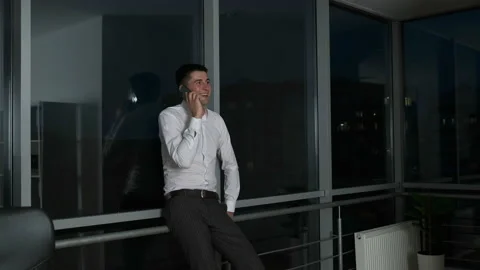 A young lawyer lingered at work until night standing by a panoramic window and Video stock 134161550