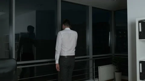 A young lawyer lingered at work until night standing by a panoramic window and Stock Footage 138583261
