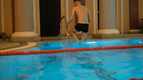 Young lean man exiting gym pool by ladder Stock Footage 333199961