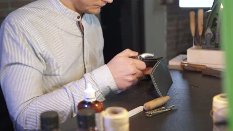 Young leather craftsman creates a DIY product. Craftsmanship workman. Men hobby. 库存影片 130214628