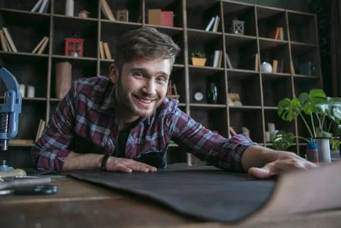 Young leather maker start work with smile on face and keep leather on table Stock Photos