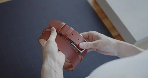 Young leather worker examining finished leather belt close-up Stock Footage 146139071
