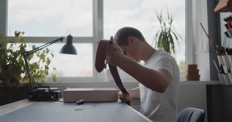 Young leather worker examining leather belt during manufacturing process Stock Footage 144892789
