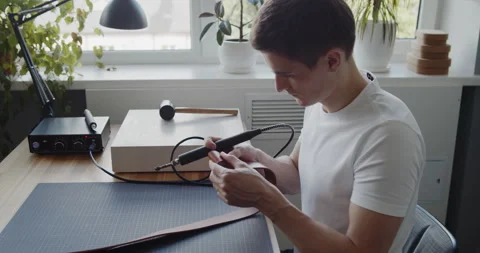 Young leather worker examining leather belt during manufacturing process Stock Footage 146134226