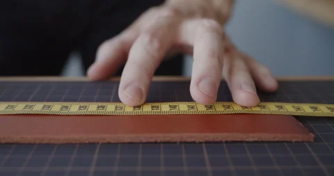 Young leather worker measuring leather strip for making a belt Stock Footage 146131739