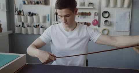 Young leather worker putting a loop on a leather belt completing its making Stock Footage 146139723
