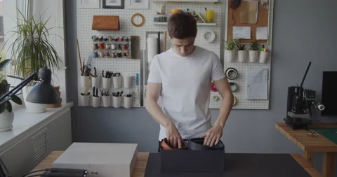 Young leather worker selects a blank for making a leather belt Stock Footage 146139407