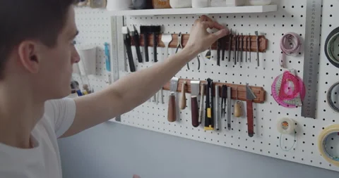 Young leather worker takes tools off a tools wall close-up Stock Footage 144893999