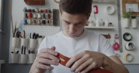 Young leather worker with vitiligo examining leather strip for making a belt Stock Footage 146134755