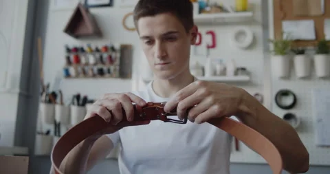 Young leather worker with vitiligo examining finished leather belt Stock Footage 146138250