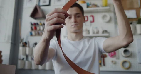 Young leather worker with vitiligo examining finished leather belt Stock Footage 146138295