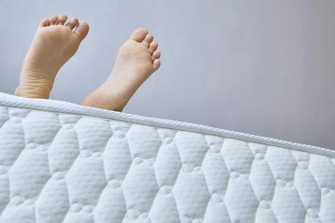 Young Legs Extend From Comfortable Mattress. Copy space Stock Photos