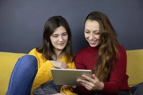 Young lesbian couple do e-commerce shopping online using tablet choosing outfits Stock Photos