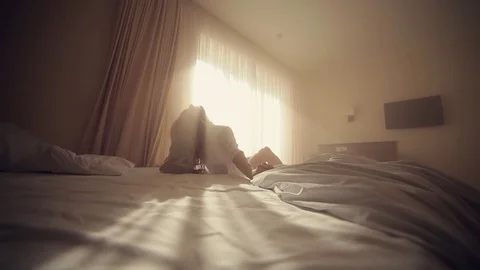 Young light blonde lying on the bed, hiding and coming to the window. girl wakes Stock Footage 128964669