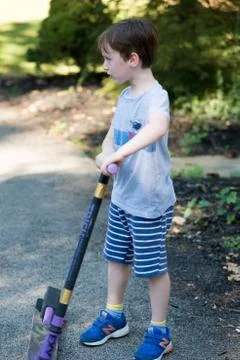 Young litte boy outside riding his scooter in the driveway Stock Photos