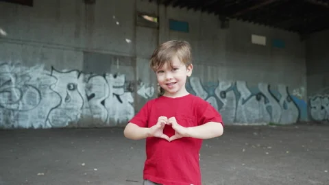 A young little boy is having fun and making heart symbols with hands and Stock Footage 161698918