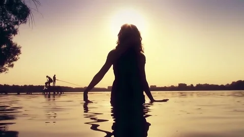 Young long hair eastern woman standing dancing and swimming at sunset in lake Stock Footage 80144053