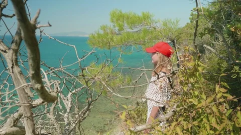 Young long haired blonde tosses her hand and points somewhere in the sea from Stock Footage 80843863