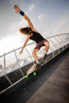 Young long-haired guy jumping high on a longboard 스톡 사진