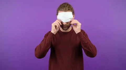 Young long haired guy shows an example of how to put on a protective medical Stock Footage 149041895