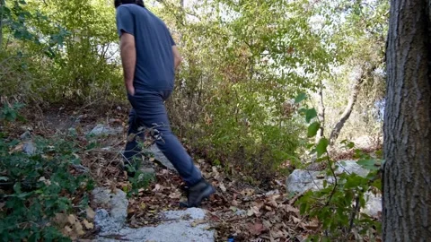 A young long-haired man trekking on the path of fallen leaves Stock Footage 141757911