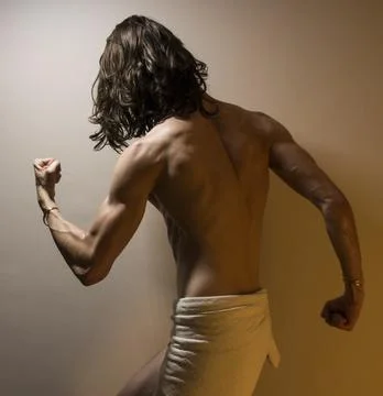 Young long haired model flexing muscles, standing in dramatic pose Stock Photos