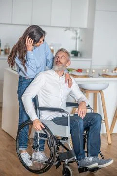 Young long-haired woman smiling nicely to her handicapped hausband and both Stock Photos