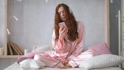 Young Long-Haired Woman Using Mobile Phone Sitting On Bed In The Morning. Stock Footage 104051041