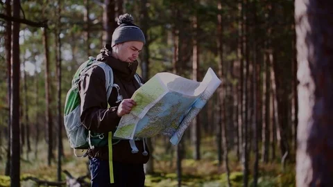 Young, lost hiker man with a map looking for direction in forest Stock Footage