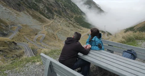 Young lovers couple rest on bench after hiking to the top of the mountain Stock Footage 298962586