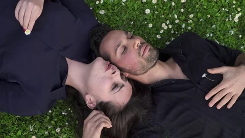 Young lovers lying on the grass talking amiably 스톡 동영상 72824411