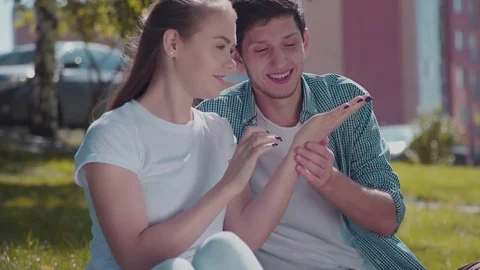 Young lovers sit on the grass look at the ladybird on the girl's palm. Stock-Footage 79953702