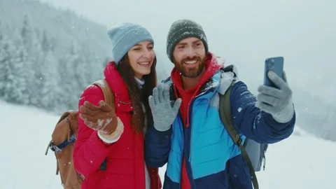 Young loving couple doing live stream for social media under snowfall in forest Stock Footage 144358208
