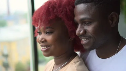 Young loving couple looking out window and kissing while standing in apartment Stock Footage 166015192