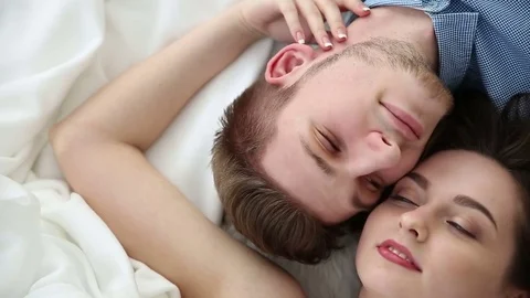 Young loving couple lying on bed at home - dolly shot Stock Footage 76245250