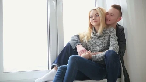 Young loving couple sitting and hugging by the window indoors 動画素材 76845839