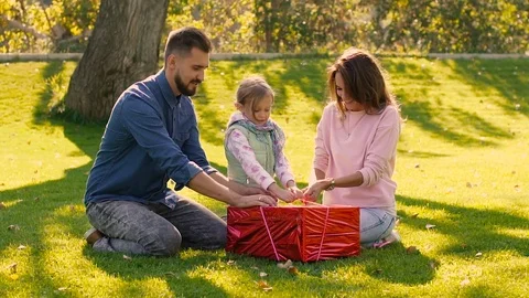 Young loving family trying to undo the ribbon of birthday present Stock-Footage 70820068