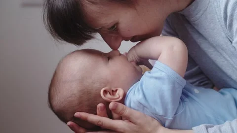 Young loving mom is playing with her newborn baby while holding him on her lap Stock Footage 150265561