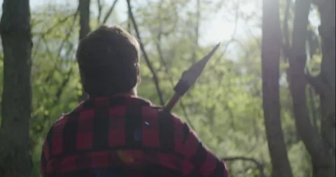 Young lumberjack with axe walking in forest Stock Footage 148178581